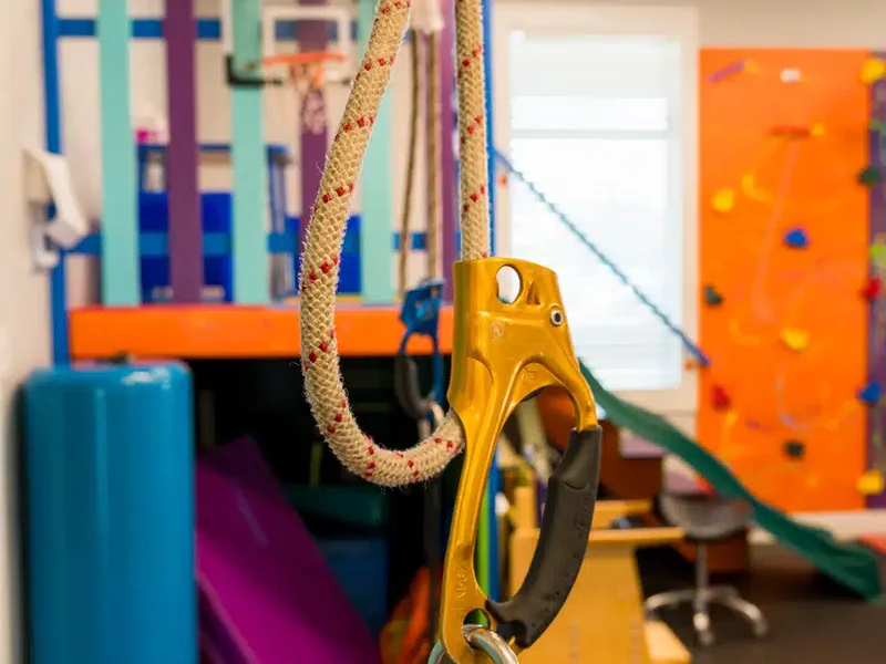 Climbing rope and clip in the gym with the orange climbing wall behind it