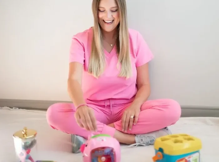Therapist seated on the floor with therapy toys ready for a session