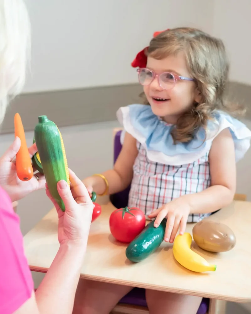 Child and therapist at a table with play food during a feeding session