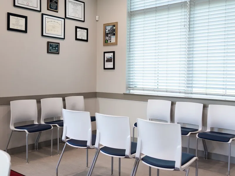 Waiting room with chairs along the wall and a window with blinds